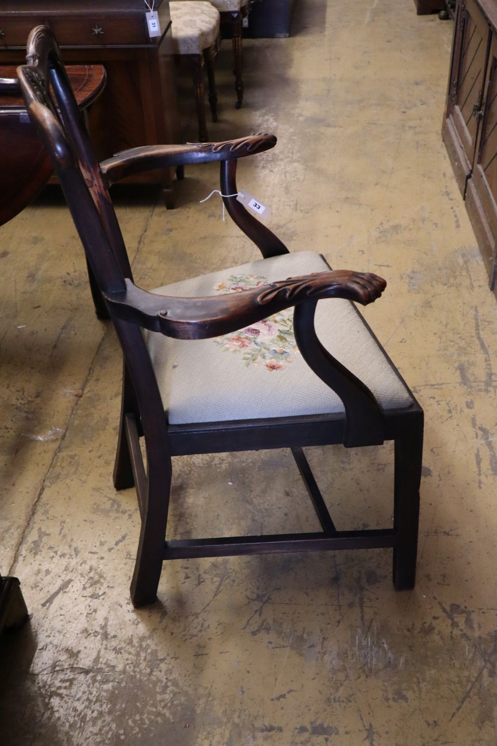 A pair of 19th century mahogany elbow chairs, scroll and leaf-carved and with lions paw armrests